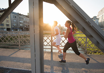 Image showing young couple jogging across the bridge in the city