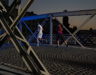 Image showing portrait of couple jogging across the bridge in the city