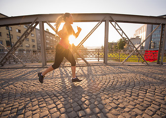 Image showing woman jogging across the bridge at sunny morning