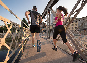 Image showing young couple jogging across the bridge in the city