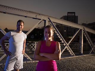 Image showing portrait of couple jogging across the bridge in the city