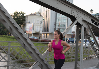 Image showing woman jogging across the bridge at sunny morning