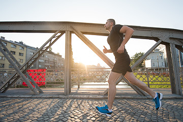 Image showing man jogging across the bridge at sunny morning