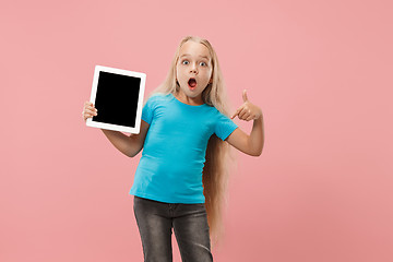 Image showing Little funny girl with tablet on pink background