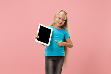 Image showing Little funny girl with tablet on pink background