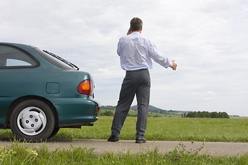 Image showing Businessman talking on cell phone beside his car