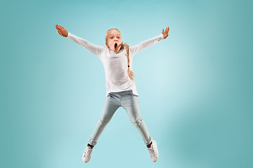 Image showing Adorable small child at blue studio. The girl is jumping and smiling.