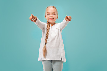 Image showing The happy teen girl pointing to you, half length closeup portrait on blue background.