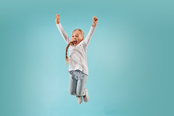 Image showing Adorable small child at blue studio. The girl is jumping and smiling.