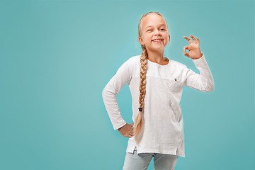 Image showing The happy teen girl standing and smiling against blue background.