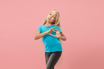 Image showing Beautiful smiling teen girl makes the shape of a heart with her hands on the pink background.