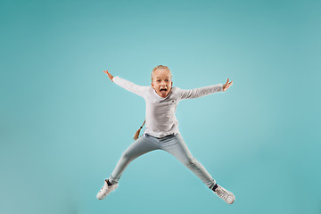 Image showing Adorable small child at blue studio. The girl is jumping and smiling.