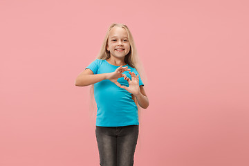 Image showing Beautiful smiling teen girl makes the shape of a heart with her hands on the pink background.