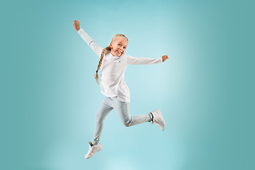 Image showing Adorable small child at blue studio. The girl is jumping and smiling.