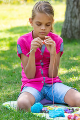 Image showing Girl knits on a knitting needles on a picnic in nature