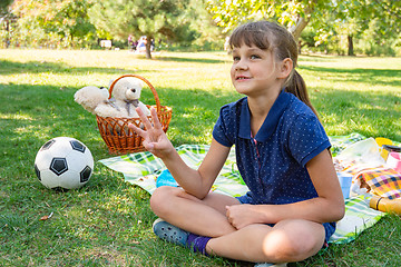 Image showing Girl on a picnic counts goals scored on fingers