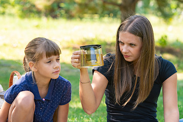Image showing Girl and girl with interest look at a teapot at a picnic