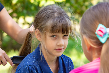 Image showing Girl trying to comb the girl\'s tightly tangled hair