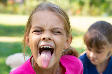 Image showing The girl turned and funny shows a long tongue