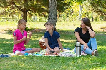 Image showing Two girls and a girl talking on a picnic