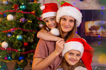 Image showing Mother and two daughters at the Christmas tree