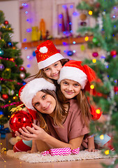 Image showing Mom and two daughters lie on the floor of a Christmas tree in the New Year\'s interior