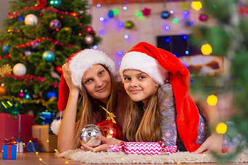 Image showing Girl and child lie on the mat in the New Year\'s interior