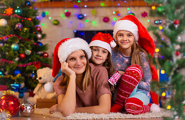 Image showing Mom and two daughters lie on the floor of a Christmas tree