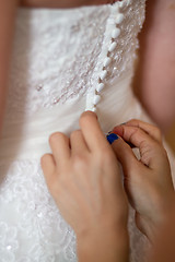 Image showing Hands of bridesmaids on bridal dress