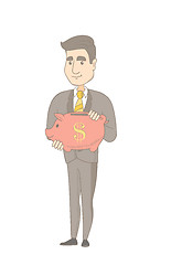 Image showing Young caucasian businessman holding a piggy bank.