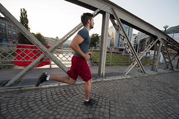 Image showing man jogging across the bridge at sunny morning