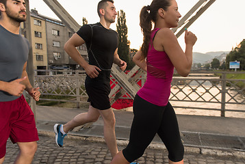 Image showing group of young people jogging across the bridge