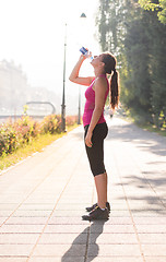 Image showing woman drinking water from a bottle after jogging