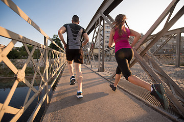 Image showing young couple jogging across the bridge in the city