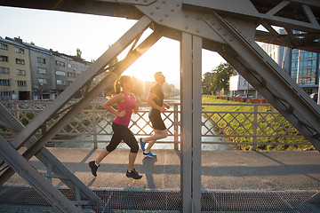 Image showing young couple jogging across the bridge in the city