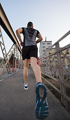 Image showing man jogging across the bridge at sunny morning