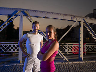 Image showing portrait of couple jogging across the bridge in the city