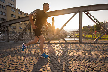 Image showing man jogging across the bridge at sunny morning