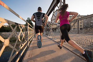 Image showing young couple jogging across the bridge in the city