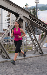 Image showing woman jogging across the bridge at sunny morning