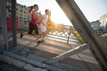 Image showing young couple jogging across the bridge in the city