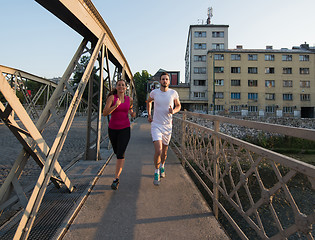 Image showing young couple jogging across the bridge in the city