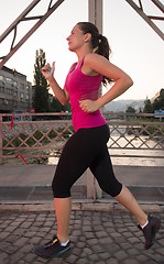 Image showing woman jogging across the bridge at sunny morning