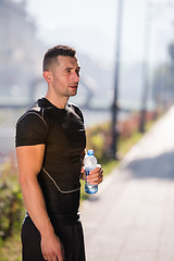 Image showing man drinking water from a bottle after jogging