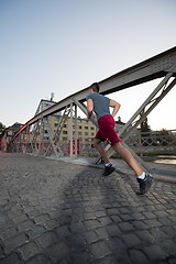 Image showing man jogging across the bridge at sunny morning