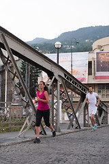 Image showing young couple jogging across the bridge in the city
