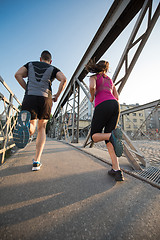 Image showing young couple jogging across the bridge in the city