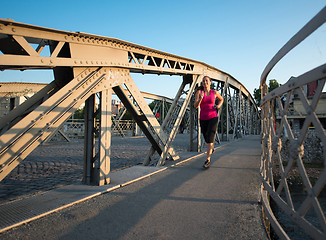 Image showing woman jogging across the bridge at sunny morning