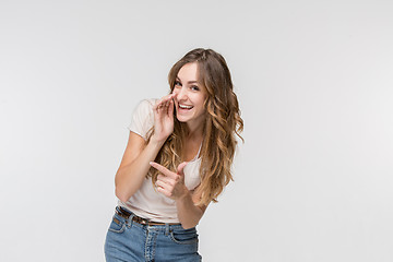 Image showing The young woman whispering a secret behind her hand