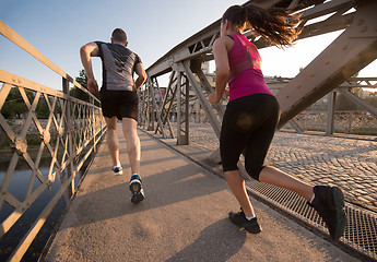 Image showing young couple jogging across the bridge in the city